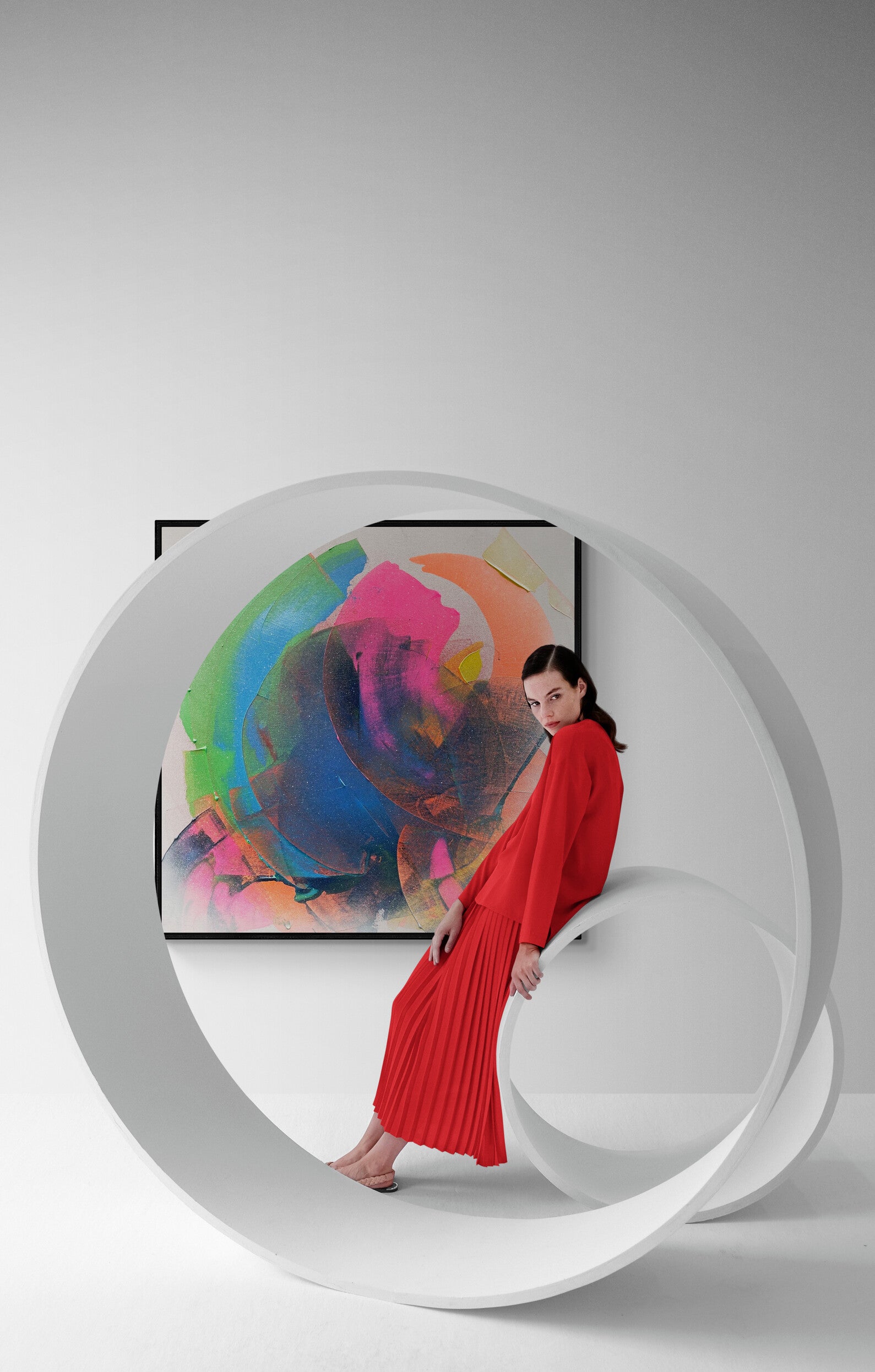 Woman in a red dress standing in front of a colorful abstract painting on a white wall.