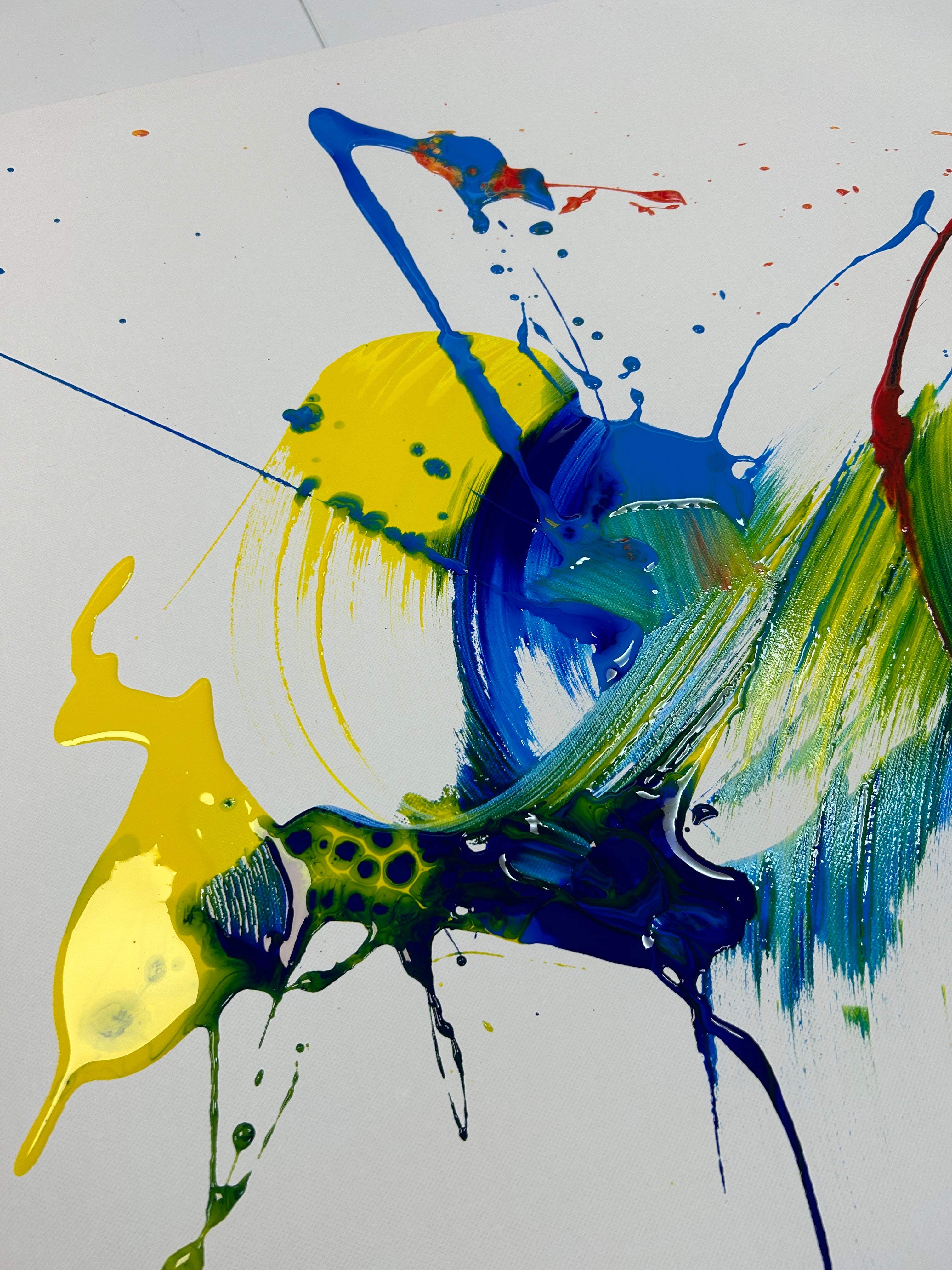 Abstract painting with splashes of yellow, blue, and green on a white background