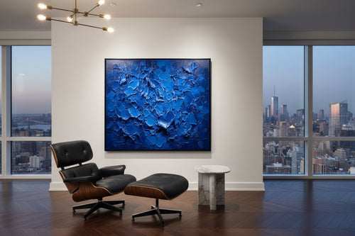 Modern interior with a blue abstract painting, Eames chair, and cityscape view.